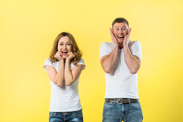 Free photo portrait of excited young couple against yellow background