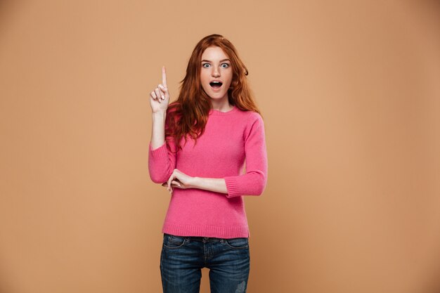 Портрет возбужденных рыжий молодой девушки, указывая пальцами