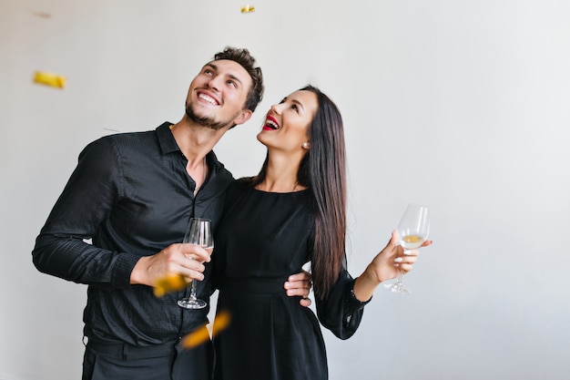 Portrait of excited young woman embracing with husband at event and posing with confetti