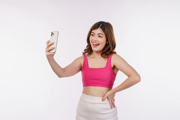 白い背景の上に分離されたスマートフォンで興奮した若い女性のビデオ通話の肖像画