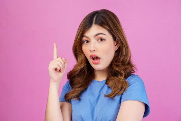 Portrait of excited young woman wearing casual tshirt thinking and imagination isolated over pink background