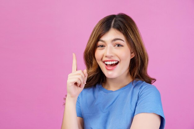 Portrait of excited young woman wearing casual tshirt thinking and imagination isolated over pink background