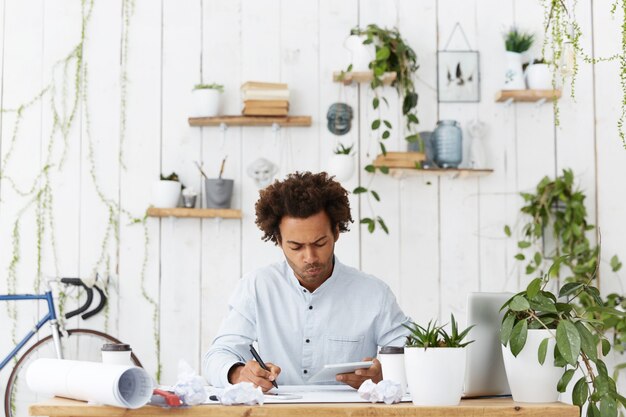 Free photo portrait of experienced skilled dark-skinned male architect analysing construction plan