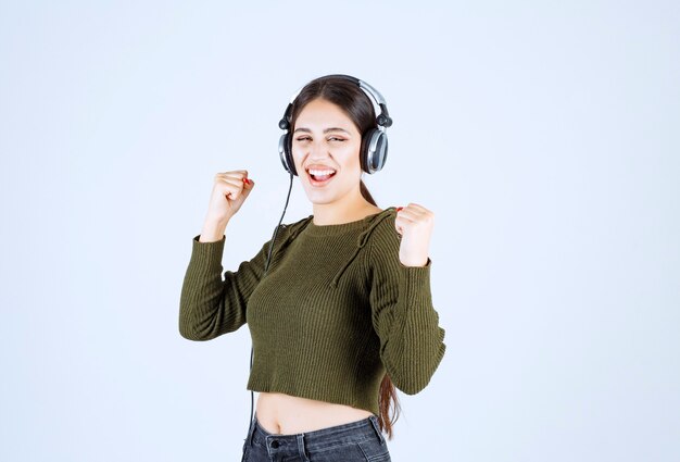 Portrait of expressive young girl listening to music and dancing.