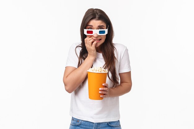 Портрет выразительной молодой женщины, едящей попкорн и в 3d очках