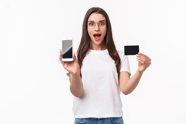 Портрет выразительной молодой женщины с мобильным телефоном и кредитной картой