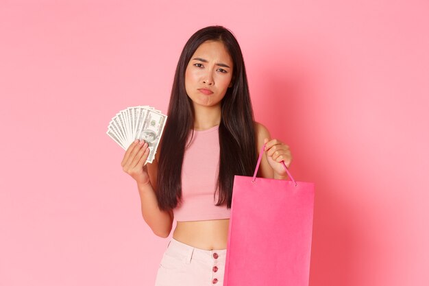 ショッピングバッグとお金を持つ肖像画表現力豊かな若い女性