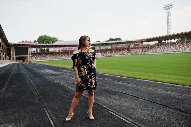 Portrait of a fabulous girl in dress and high heels on the track at the stadium