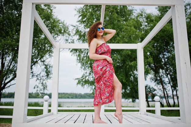 Portrait of a fabulous young girl wearing chic outfit posing on a white wooden terrace