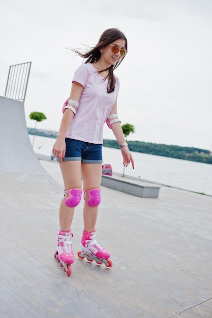 Foto gratuita ritratto di una giovane donna favolosa con i rollerblade sulla pista di pattinaggio a rotelle all'aperto