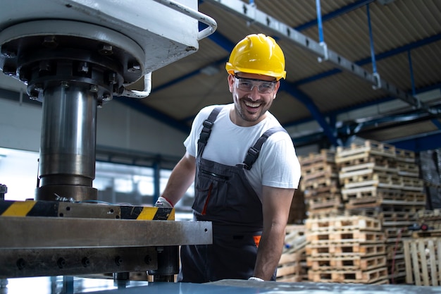 Портрет фабричного рабочего со скрещенными руками, стоя у сверлильного станка на промышленном предприятии