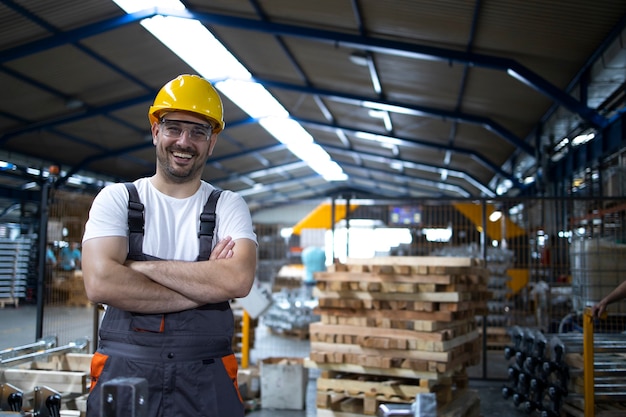 Portrait of factory worker with arms crossed standing by industrial machine