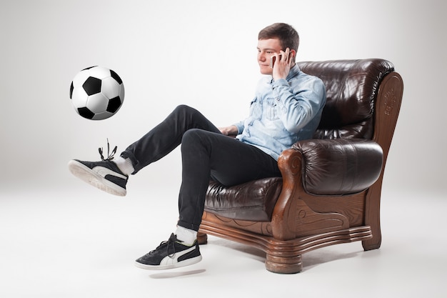 portrait of fan with ball, holding  tv remote on white