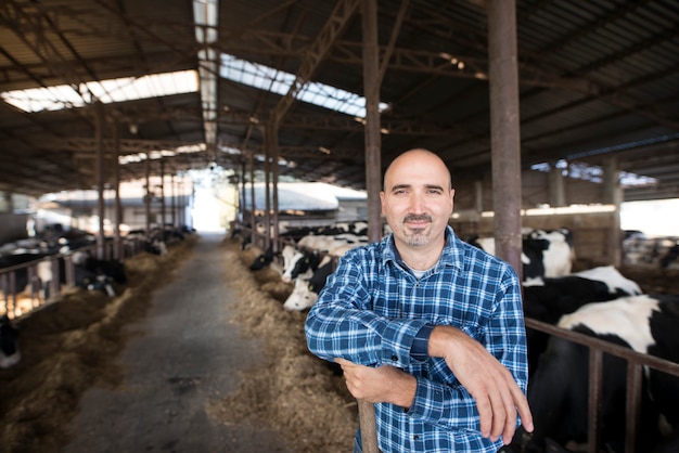 Foto gratuita ritratto di lavoratore agricoltore in piedi presso l'allevamento di bestiame