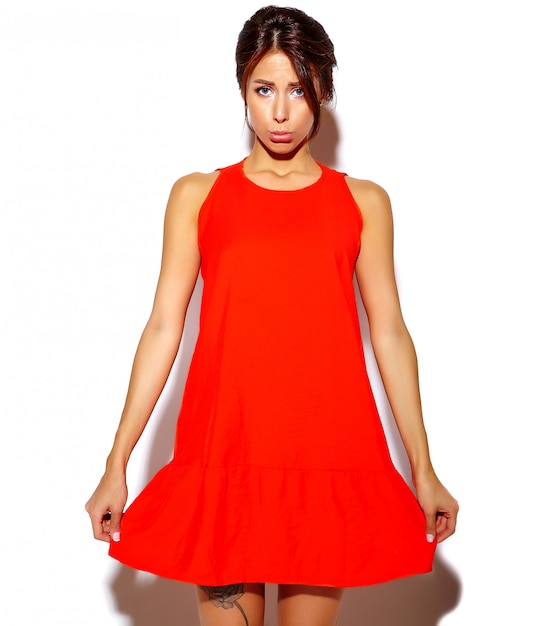 Портрет модели милой молодой женщины моды в красном платье на белой стене