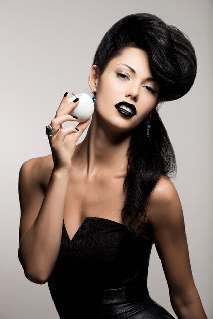 Portrait of fashion woman with modern hairstyle and  lips in black color with white apple