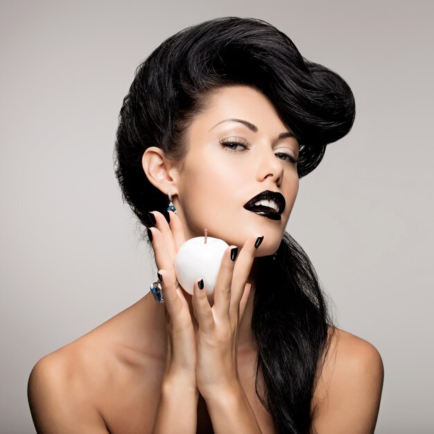 Портрет модной женщины с современной прической и губами черного цвета с белым яблоком