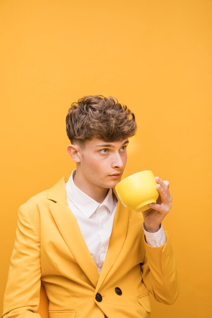 Портрет модного мальчика, пьющего из чашки