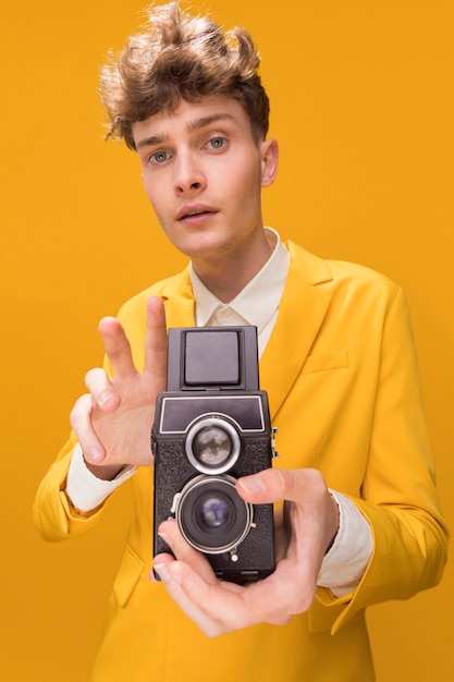 Free photo portrait of fashionable boy filming with a camcorder