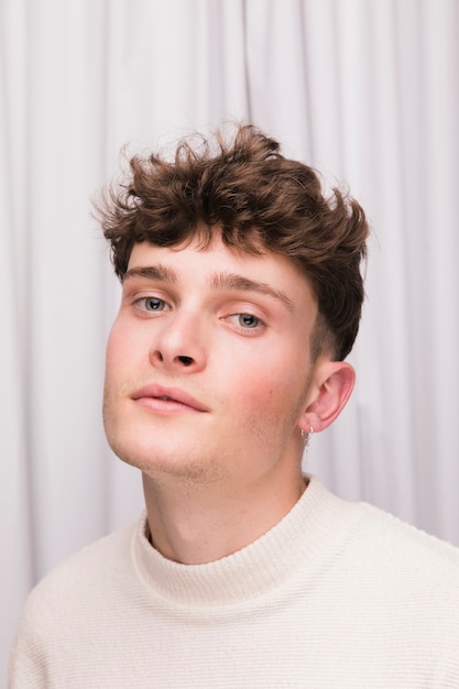 Portrait of fashionable boy in front of white curtain