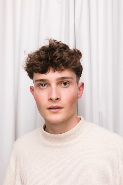 Free photo portrait of fashionable boy in front of white curtain