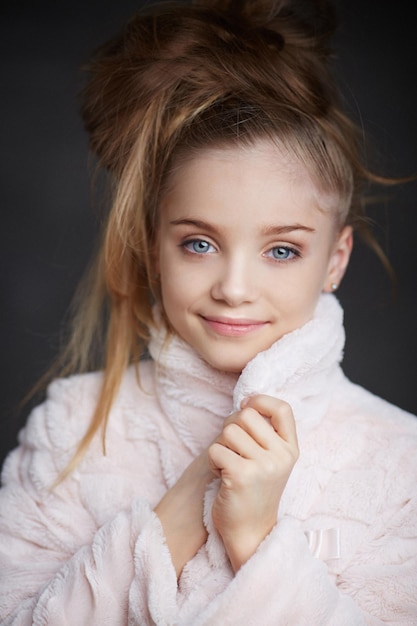 Портрет модной маленькой девочки в белом пальто с длинными волосами