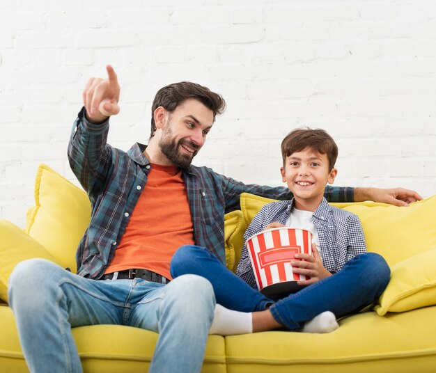 Portrait of father and son sitting on sofa