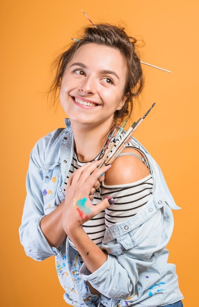 Free photo portrait of female artist with paintbrushes