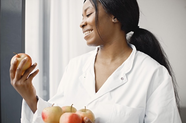 Portrait of female black doctor standing and holding apples