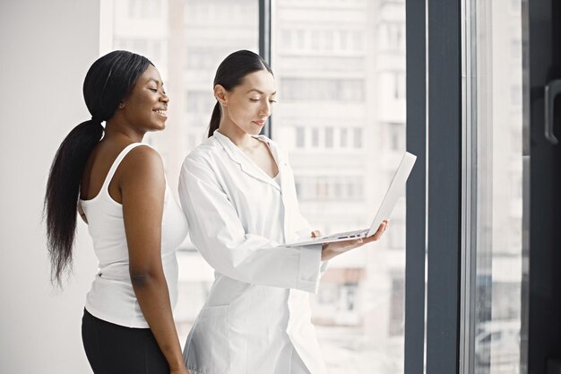 클리닉 사무실에 서 있는 백인 여성 의사와 흑인 환자의 초상화