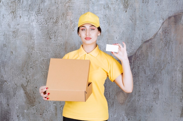 Portrait of female courier holding card with cardboard box