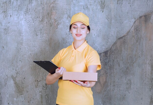 Portrait of female courier holding clipboard with cardboard box