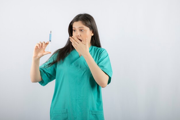 Portrait of female doctor holding a large syringe. 