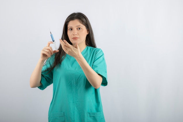 Portrait of female doctor holding a large syringe. 