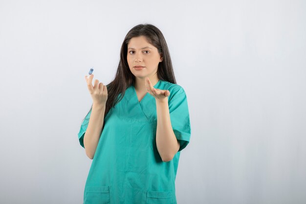 Portrait of female doctor holding a large syringe. 