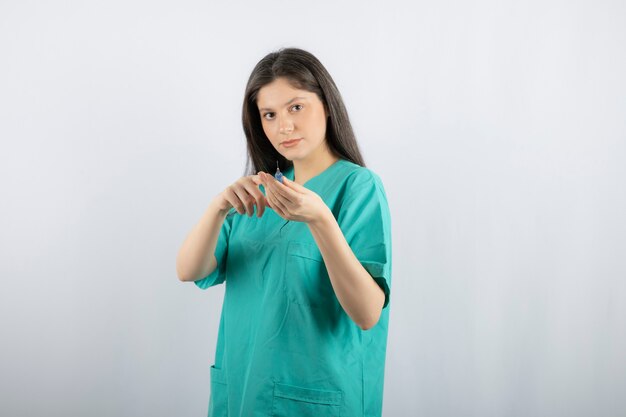 Portrait of female doctor holding a large syringe. 