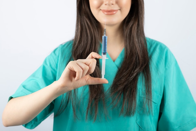 Ritratto di medico femminile che tiene una grande siringa. .