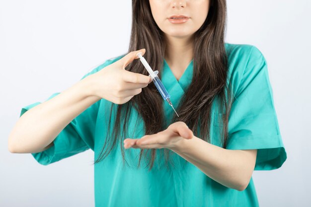 Portrait of female doctor holding a large syringe. 