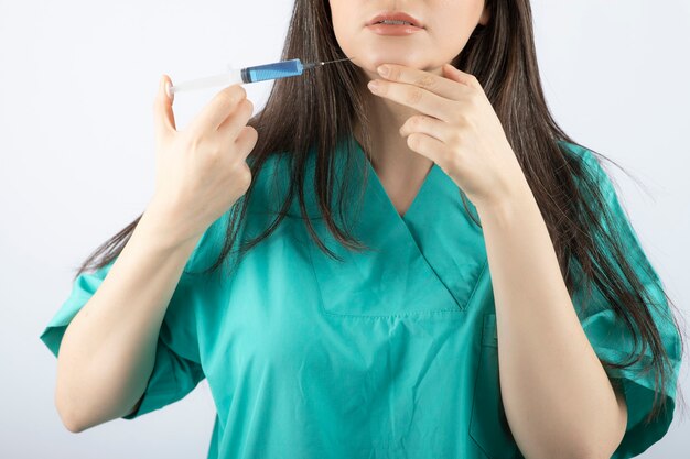 Portrait of female doctor holding a large syringe. 