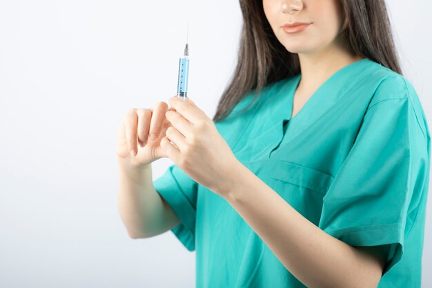 Portrait of female doctor holding a large syringe. 