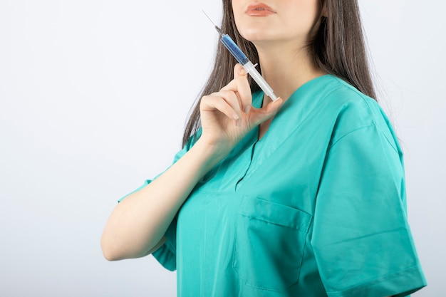 Portrait of female doctor holding a large syringe. 