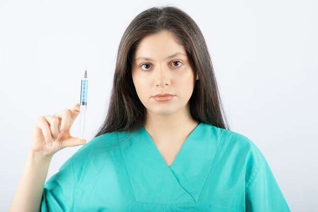 Portrait of female doctor holding a large syringe. 