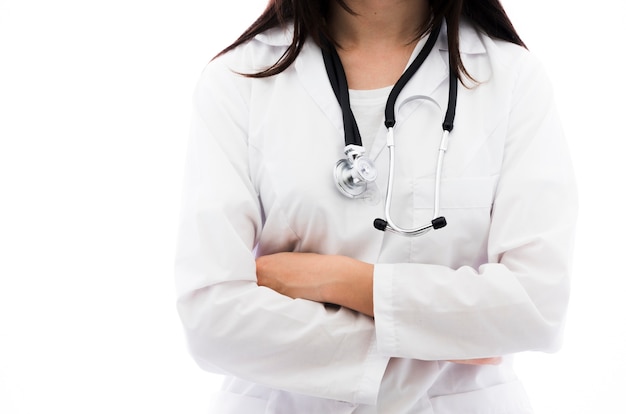 Portrait of a female doctor holding stethoscope around her neck with arm crossed against white backdrop