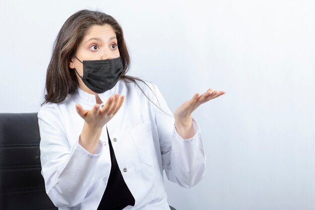 Portrait of female doctor in medical mask and white coat arguing with someone.