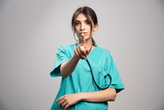 Portrait of female doctor posing with stethoscope on gray