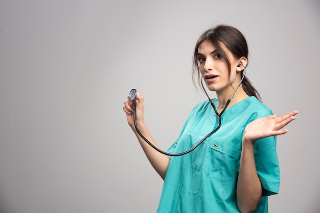 Портрет женщины-врача удивлен результатами на сером
