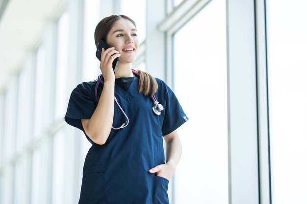 Портрет женщины-врача, использующей мобильный телефон в своем больничном кабинете