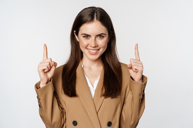 Free photo portrait of female entrepreneur corporate woman pointing fingers up smiling confident showing advert...