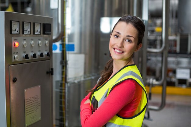 Portrait of female factory worker standing near machine