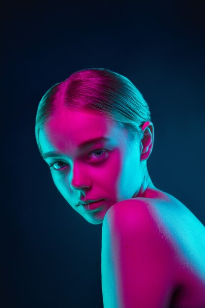 Portrait of female fashion model in neon light on dark studio